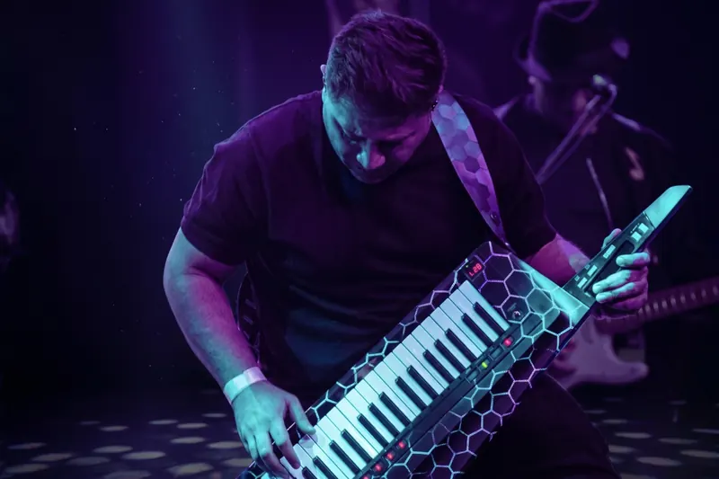 Keytar player mid-solo under purple light